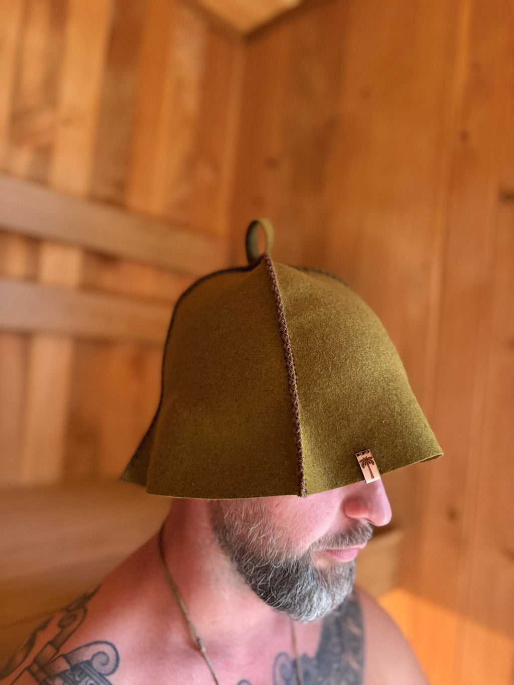 person wearing green wool sauna hat in sauna
